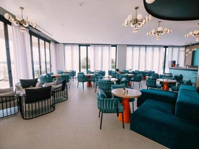 Lichte moderne hotelruimte met blauwe stoelen en grote ramen met uitzicht.