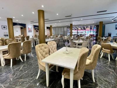 Elegantní restaurace s pohodlnými židlemi a mramorovou podlahou v světlém interiéru.