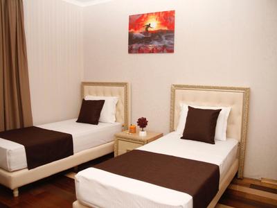 Kleines Schlafzimmer mit zwei Einzelbetten, braunen Deckenläufern und einem Nachttisch dazwischen.