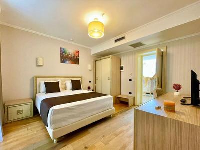 Helles Schlafzimmer mit Doppelbett, Holzfußboden, Kommode, TV und Bild an der Wand.