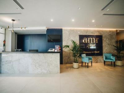 Lobby d'hôtel moderne avec réception en marbre et fauteuils bleus devant un mur doré.
