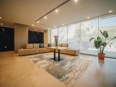 Espace lounge hôtel moderne avec grandes fenêtres et coin salon beige.