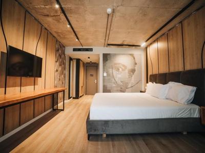 Modernes Schlafzimmer mit großem Bett, Wandkunst, Holzboden und TV an der Wand.