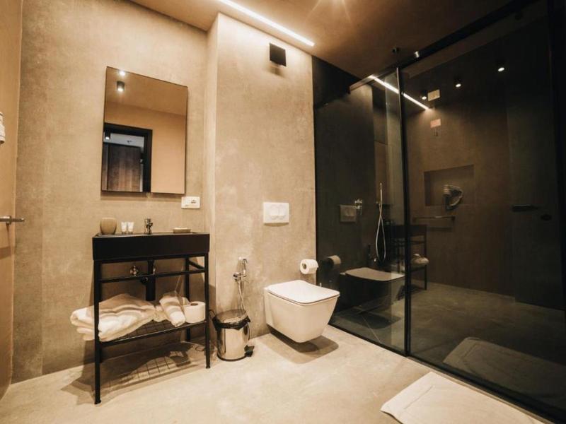 Modernes Badezimmer mit heller Wand, schwarzem Waschbecken, Spiegel und Glasdusche.