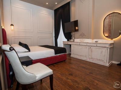 Elegantes Schlafzimmer mit rotem Bett, weißem Stuhl, großem Spiegel und Holzboden.