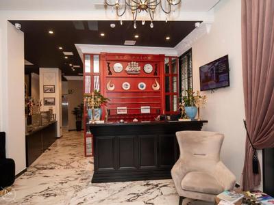 Elegancka recepcja hotelowa z czarnym kontuarem, czerwoną ścianą i wygodnymi miejscami do siedzenia.