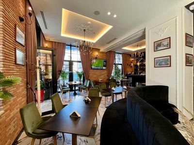 Nowoczesna przestrzeń lounge w hotelu z stołami, krzesłami i stylowym oświetleniem.