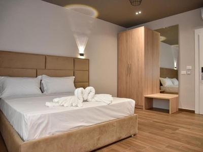 Chambre d'hôtel moderne avec lit double, sol en bois et grand miroir près de la porte.