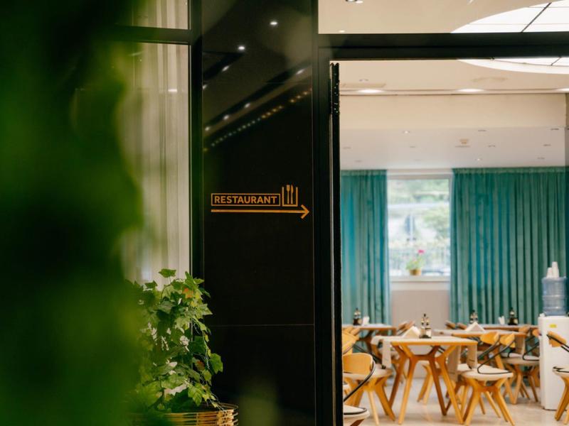 View through a door into a room with teal curtains and wooden tables in a hotel.