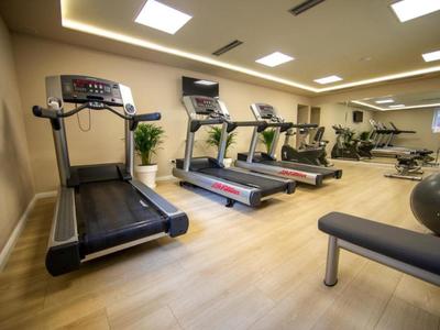 Palestra moderna con tapis roulant, cross trainer e panca da allenamento in un hotel.
