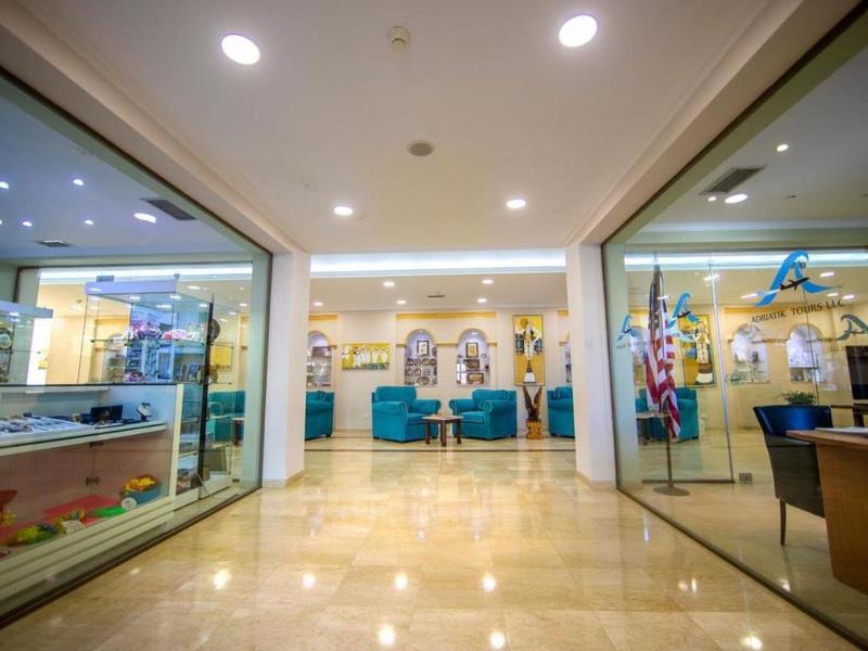 Jasna, nowoczesna lobby hotelowa z częścią wypoczynkową i szklanymi drzwiami po obu stronach.