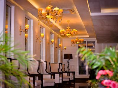 Eleganter Hotelflur mit goldenen Kronleuchtern und Stühlen an der Wand