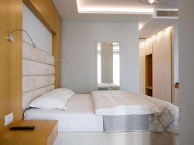 Camera d'hotel moderna con letto matrimoniale, grande specchio e illuminazione calda.