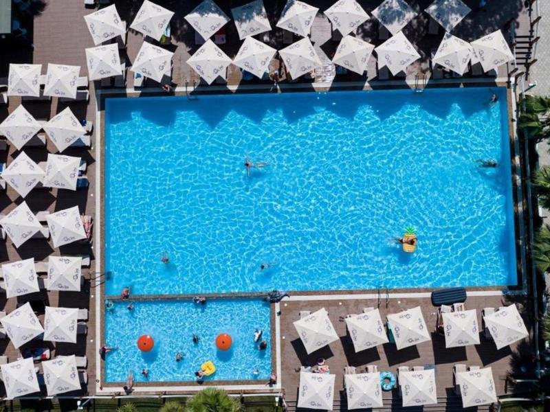 Vista aerea di una grande piscina con ombrelloni e bagnanti nell'area dell'hotel.