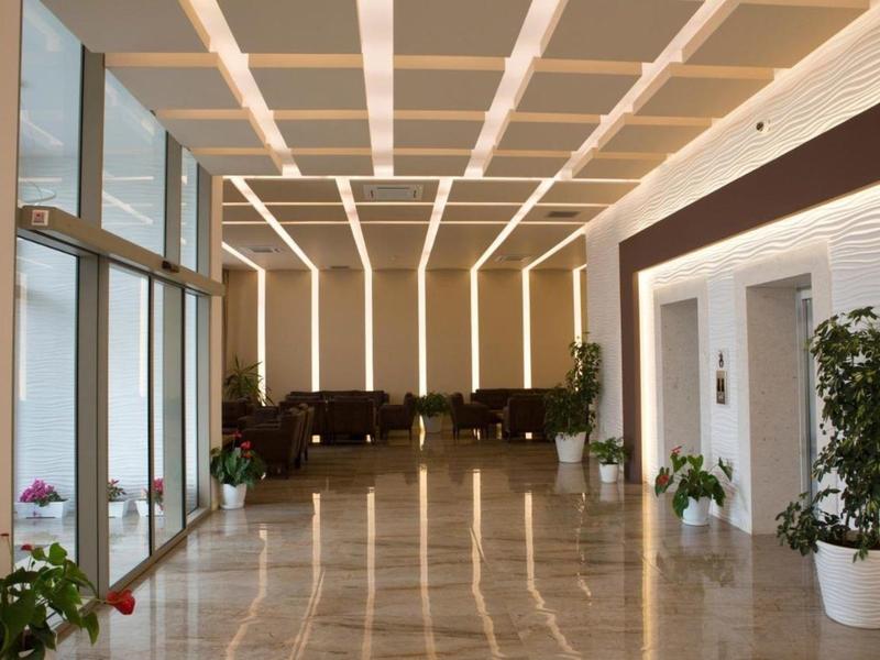 Luminosa hall dell'hotel con luci moderne a soffitto, area salotto e piante.