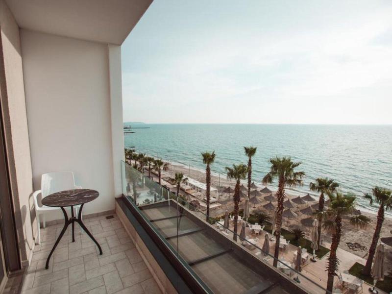 Balcone con tavolo e due sedie con vista sulla spiaggia e sul mare al tramonto.