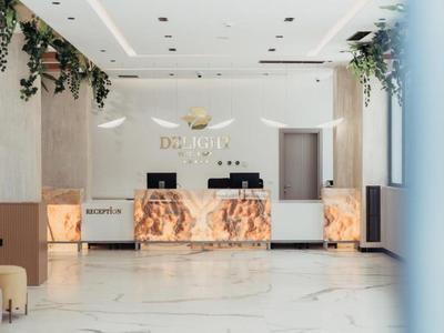 Modern hotel reception with marble front desk and decorative plants on the ceiling.