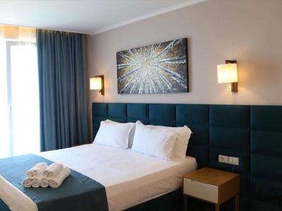 Camera d'hotel moderna con letto matrimoniale, testiera blu e decorazione astratta a muro.