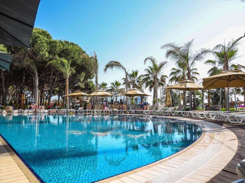 Grande piscina dell'hotel con lettini e palme sotto un cielo sereno