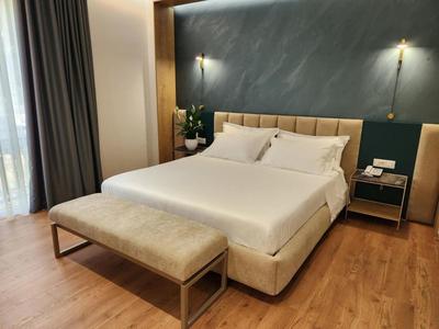 Nowoczesny pokój hotelowy z podwójnym łóżkiem, tapicerowaną ławką i drewnianą podłogą.