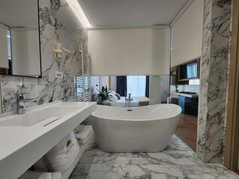 Elegancka łazienka z wolnostojącą wanną i marmurowymi ścianami w nowoczesnym pokoju hotelowym.