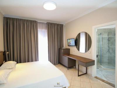 Modern hotel room with double bed, desk, mirror, and adjoining bathroom.