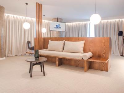 Sala moderna con panca in legno, cuscini e tavolino minimalista con luce calda.