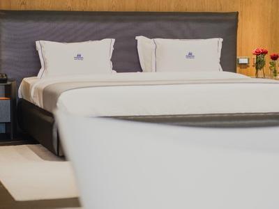 Camera d'albergo moderna con un grande letto matrimoniale e cuscini decorativi.