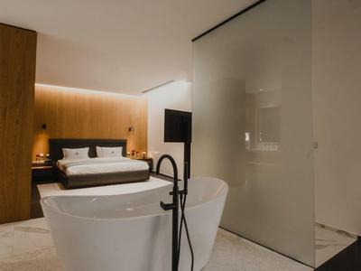 Camera d'hotel moderna con vasca da bagno autonoma e letto matrimoniale accogliente.