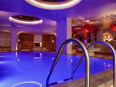 Piscina indoor in hotel con illuminazione blu e design moderno.