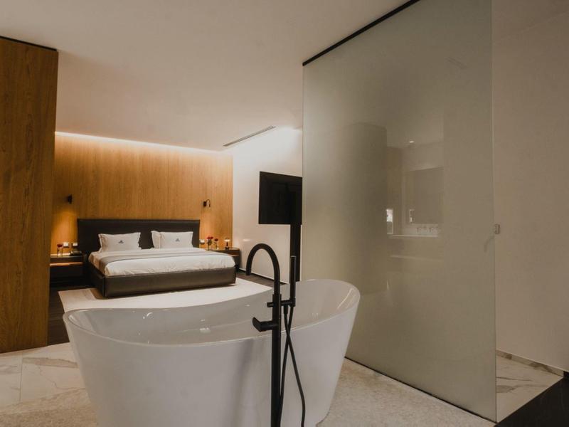 Camera d'hotel moderna con vasca da bagno autonoma e letto matrimoniale accogliente.