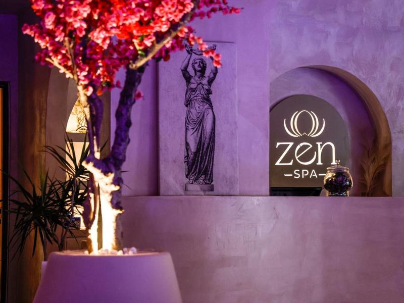 Area spa elegante con candele, scultura e ramo fiorito.