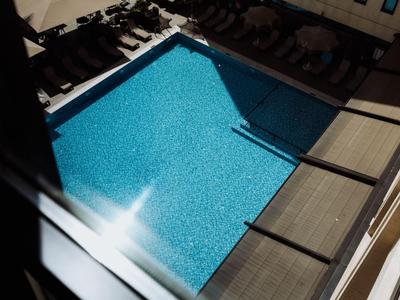 Piscine extérieure avec eau bleue et transats sur terrasse en bois à côté de l'hôtel.