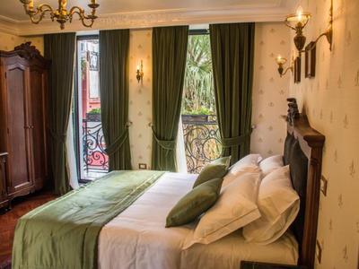 Gezellige hotelkamer met tweepersoonsbed, groene gordijnen en houten meubels.