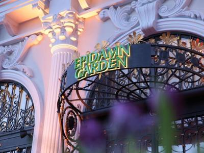 Gevel met sierlijke zuilen en een bord met de tekst 'Erdvavin Garden' bij warm licht.