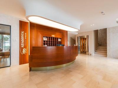 Moderner Hotel-Empfangsbereich mit Holztheke und beleuchtetem Eingangsschild.