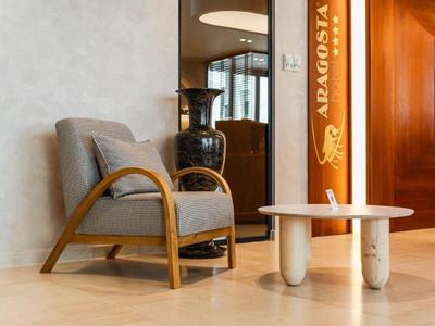 Moderner Sessel mit Holzakzenten neben weißem Tisch in elegantem Hotellobbybereich.