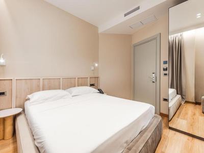 Modernes Hotelzimmer mit Doppelbett, hellen Wänden und Holzboden.