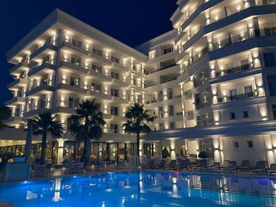 Illuminated hotel building with balconies and pool at night.