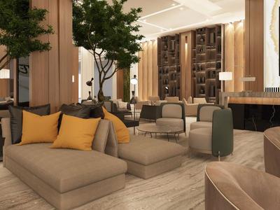 Modernly furnished hotel lounge with comfortable sofas, trees, and warm lighting.