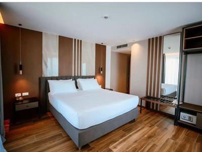 Modern hotel room with double bed, wooden floor, and neutral wall decor.