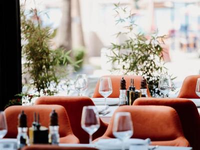 Elegant restaurant with modern decor and tables set with wine glasses and plants