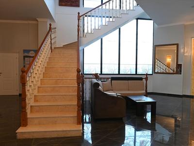 Interior moderno con escalera de madera clara y área de descanso junto a una ventana grande.