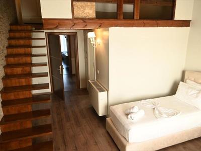 Habitación moderna con cama individual, escalera de madera y suelo laminado.