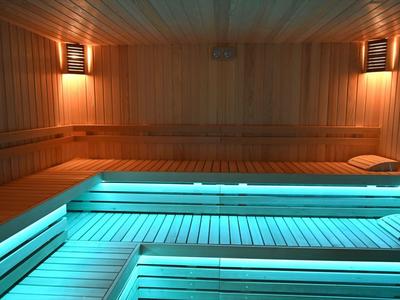 Sala de sauna con bancos de madera y luz cálida en las paredes.
