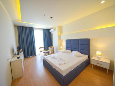 Modern eingerichtetes Hotelzimmer mit Doppelbett, Schreibtisch und großen Fenstern mit Vorhängen.