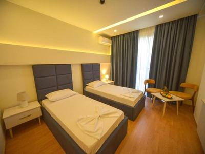 Modernes Hotelzimmer mit zwei Einzelbetten, Nachttisch und Sitzbereich mit Stühlen und Tisch.