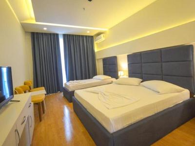 Modernes Hotelzimmer mit Doppelbett, Fernseher, Schreibtisch und gedimmtem Licht.