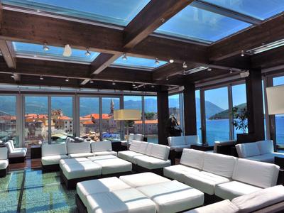 Salón moderno con sofás blancos y techo de vidrio con vistas al mar y montañas