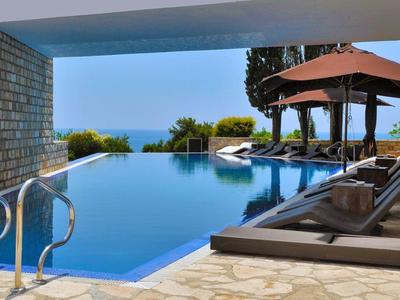 Infinity-Pool mit Meerblick, Sonnenliegen und Pavillon in einem modernen Hotel.